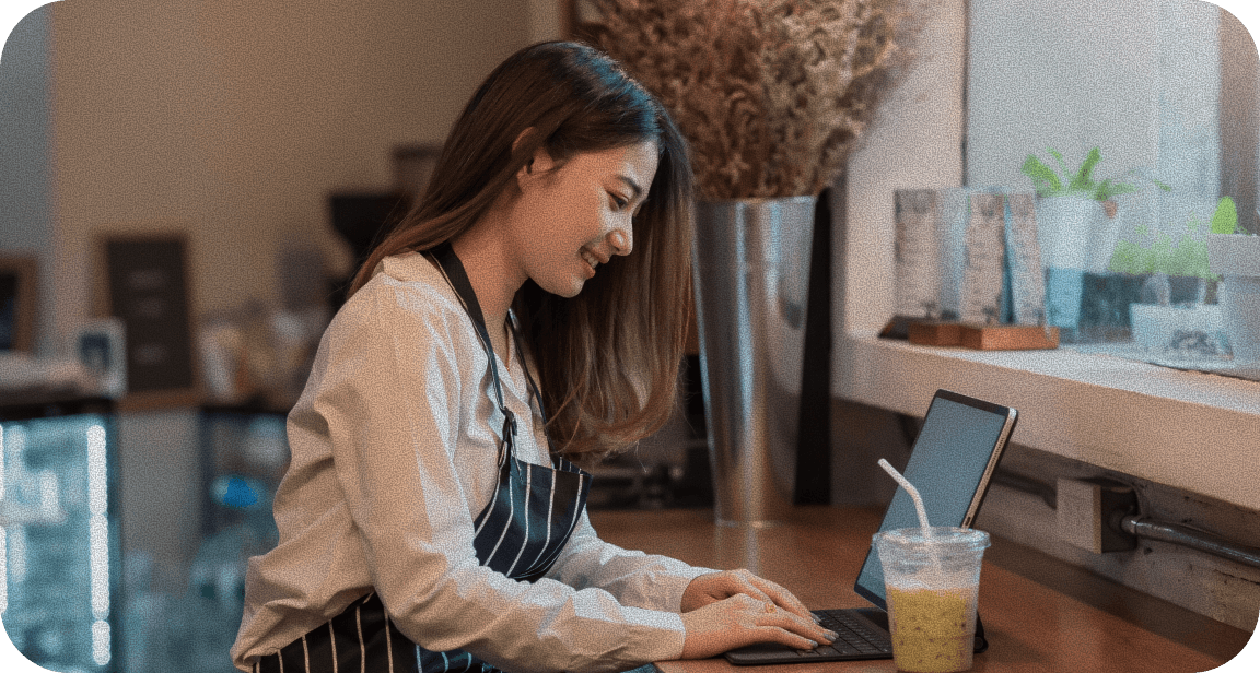 A woman happily managing restaurant operations via laptop